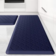 two blue bath mats sitting on top of a white floor in front of a stove