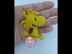 a small yellow crocheted animal is sitting on someone's hand and it appears to be smiling