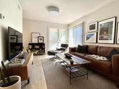 a living room with couches, tables and pictures on the wall in front of it