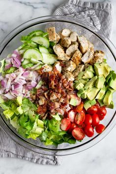 a salad with chicken, lettuce, tomatoes, cucumbers and onions