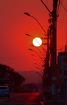 the sun is setting over a city street with power lines and telephone poles on both sides