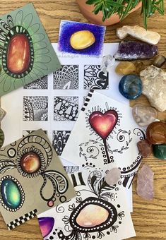 several cards and stones on a table with plants in the backgroufground