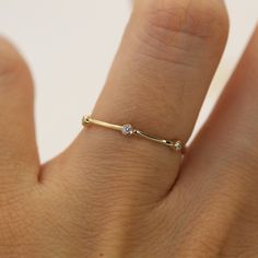 a woman's hand with a gold ring on it and a diamond in the middle