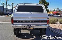 the rear end of a silver chevrolet truck parked in a parking lot with palm trees