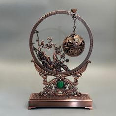 an intricately designed metal object with a green stone