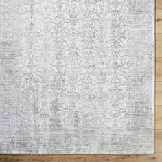 a white rug on top of a wooden floor next to a lamp shade and wood floor