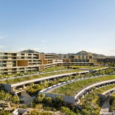 an aerial view of a building with green roofing and mountains in the back ground