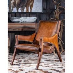 a brown leather chair sitting on top of a rug next to a table and painting