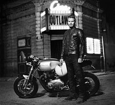 a man standing next to a motorcycle in front of a theater sign with the word outland on it