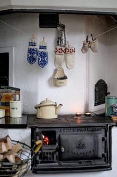 a stove top oven sitting inside of a kitchen next to a wall with hanging tea kettles