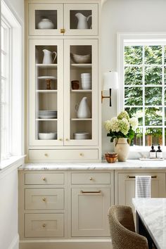 a kitchen filled with lots of white cupboards and counter top space next to a window