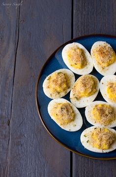 an overhead shot of deviled eggs on a blue plate with parmesan cheese