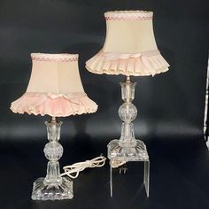 two glass lamps with pink shades on them and a white corded lamp in the middle