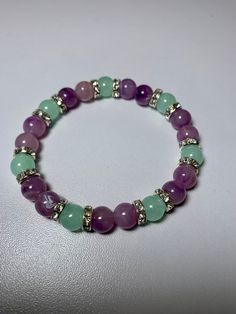 Size: 7 inch Adorn your wrist with the vibrant hues of nature with this enchanting Beaded Bracelet in shades of purple and green. Each bead in this bracelet is carefully selected to showcase the beauty of these two complementary colors, creating a harmonious and eye-catching design. The rich purples evoke a sense of royalty and mystique, while the lush greens bring to mind lush foliage and renewal. Strung together on a sturdy elastic cord, this bracelet offers both style and comfort, allowing you to wear it all day with ease. Whether you're adding a pop of color to your everyday ensemble or looking for the perfect accessory to complement your evening attire, this Beaded Bracelet in purple and green is sure to make a statement wherever you go. Purple And Green Bracelet, Purple Beaded Crystal Bracelet For Friendship, Adjustable Purple Stretch Bracelet With Natural Stones, Adjustable Green Amethyst Jewelry, Green Amethyst Round Bead Jewelry, Adjustable Multicolor Amethyst Bracelet, Adjustable Multicolor Amethyst Bracelets, Green Amethyst Beaded Jewelry, Multicolor Amethyst Beaded Bracelets For Spiritual Wear