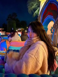 a woman sitting in an amusement park at night