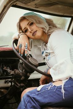 a woman sitting in the driver's seat of a truck with her hand on the steering wheel