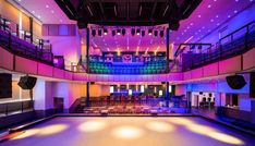 an empty dance floor is lit up with bright lights and chairs in the middle of the room