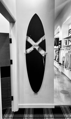 a black and white photo of a surfboard hanging on the wall in a store