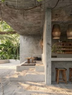 an outdoor bar with stools and tables in the middle of a concrete area surrounded by palm trees