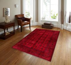 a living room with a large red rug on the floor next to a brown chair