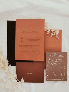 the wedding stationery is laid out on top of each other, including an orange and black card