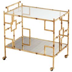 a glass table with gold metal frame and wheels on the bottom, in front of a white background