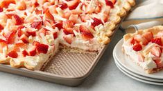 a strawberry cream pie on a plate next to a tray with slices cut out and ready to be eaten