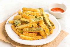 some fried food on a white plate with dipping sauce in the bowl next to it