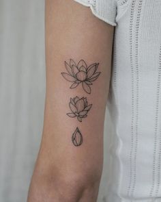 a woman's arm with three lotus tattoos on the left side of her arm