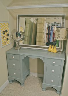 a desk with a mirror, lamp and pictures on the wall