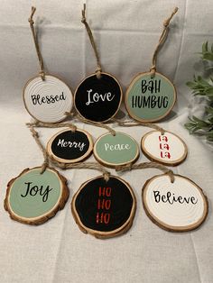 wood slice ornaments with sayings on them sitting on a white tablecloth next to a potted plant