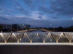 a bridge that is next to a body of water in the night time with lights on it