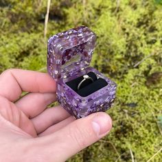 a person holding a ring in a purple box