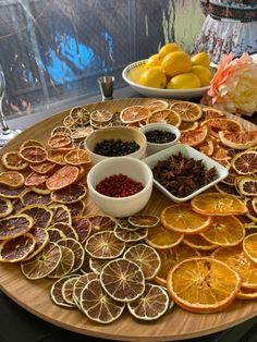 an assortment of citrus fruits and spices on a wooden platter next to wine glasses