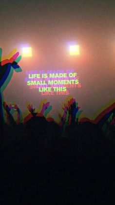 the silhouettes of people at a concert are shown in front of bright colored lights that read, life is made of small moments like this