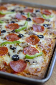 a pizza with pepperoni, black olives and green peppers