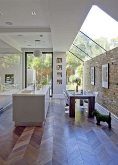 an open kitchen and dining room with large windows on the side of the house, along with hardwood flooring