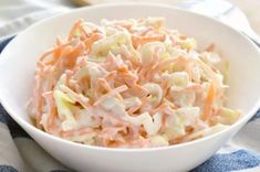 a white bowl filled with coleslaw on top of a blue and white towel