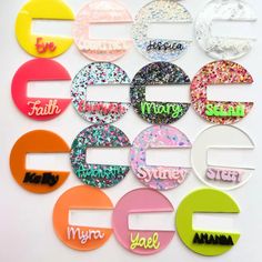 a group of different colored hair clips with name tags on them, all in different shapes and sizes