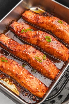 four salmon fillets in a pan with sauce and seasoning on the side, ready to be cooked