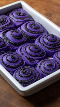 a pan filled with purple cupcakes on top of a wooden table