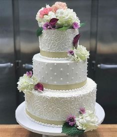 a three tiered wedding cake with white frosting and flowers on the top layer