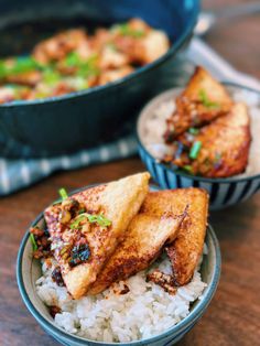 two bowls filled with rice and meat on top of a wooden table next to another bowl full of food