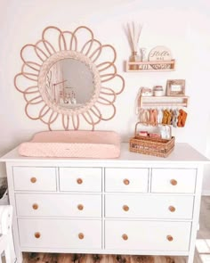 a white dresser topped with a baby crib next to a mirror