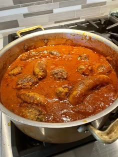 a large pot filled with meatballs and sauce on top of a stove burner