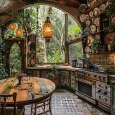 an old fashioned kitchen with lots of pots and pans hanging from the ceiling, surrounded by greenery