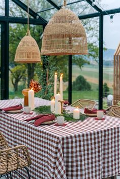 the table is set for two with candles and place settings in front of an open glass wall