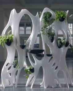 a woman walking past a tall white sculpture with plants growing on it's sides