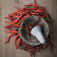 carrots and other vegetables are arranged on a wooden table with a mortar in the center