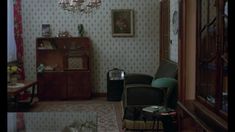 a living room filled with furniture and a chandelier hanging from the ceiling over a window